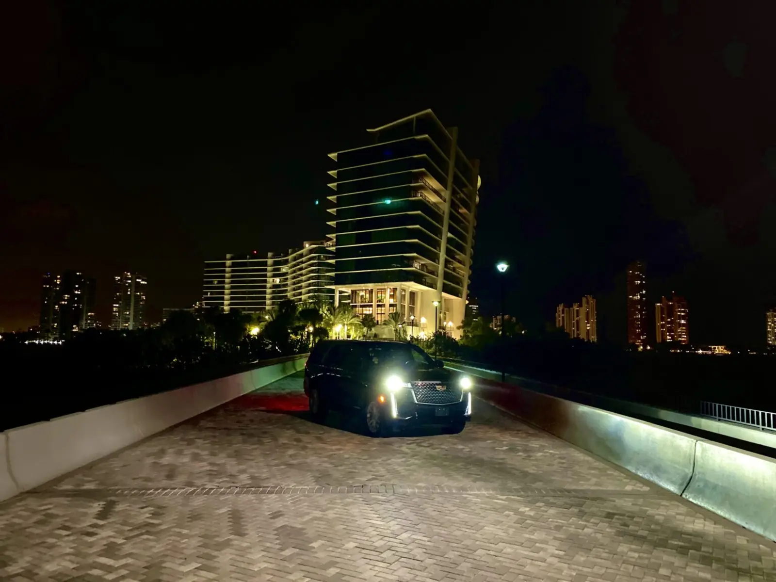 SUV nero con autista davanti a un grattacielo di Miami di notte